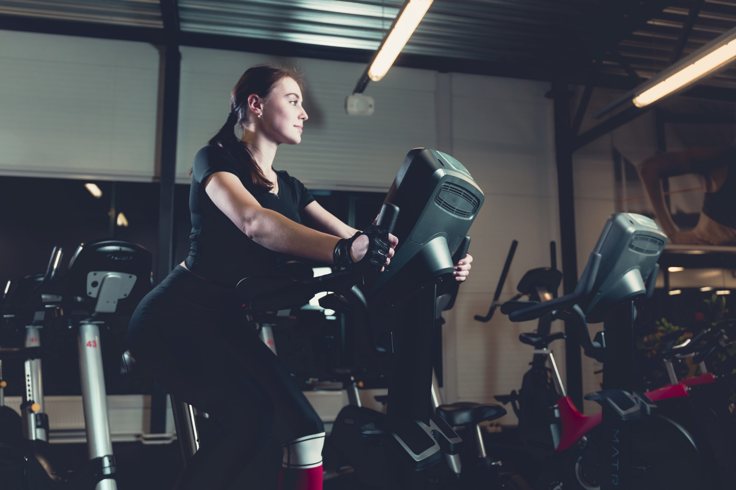 side-view-young-woman-riding-exercise-bike-gym